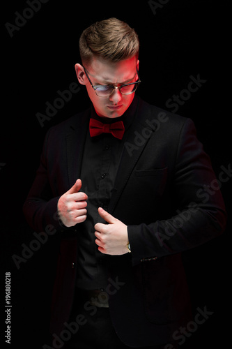 Portrait of confident handsome elegant responsible businessman with hands on his jacket on black background