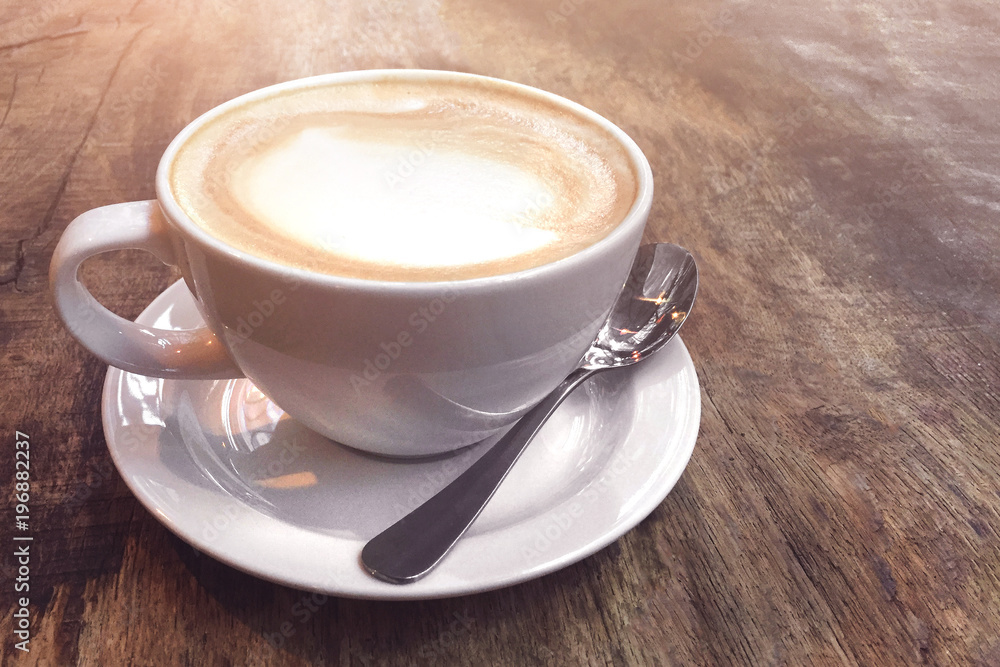 White cup with coffee on a wooden background illuminated by sun. White cup with coffee on a wooden background illuminated by sun.