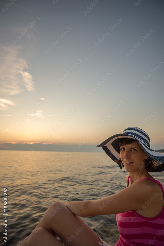 Woman sitting on the shore looking to the camera