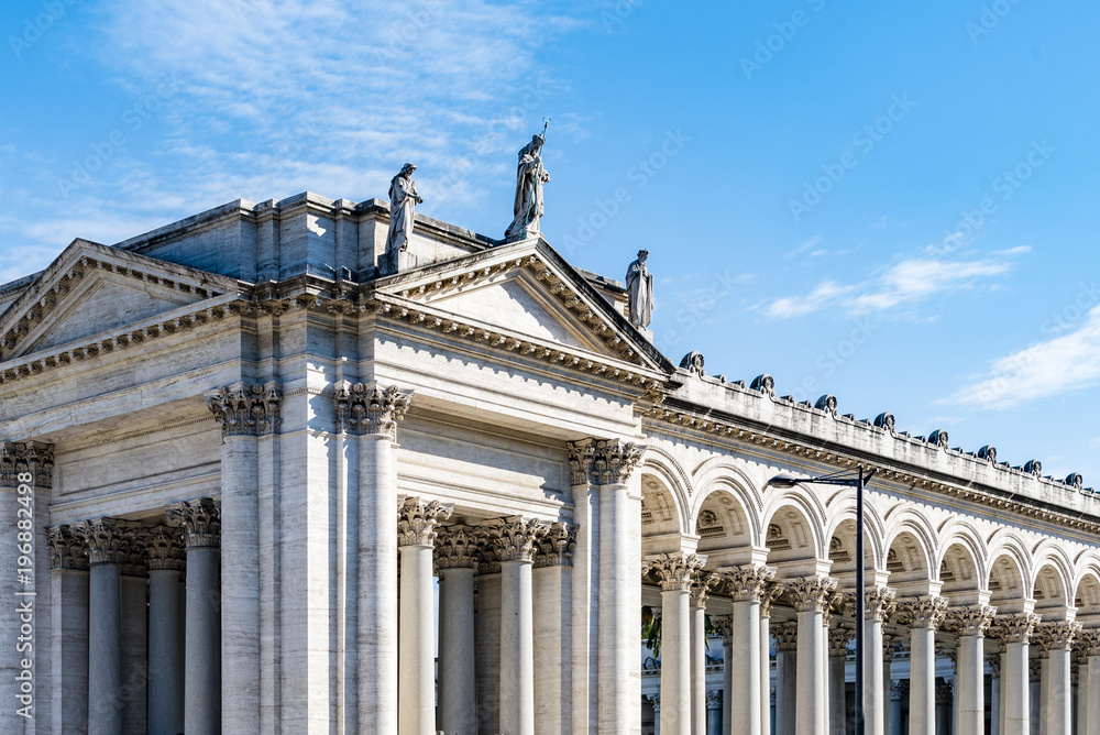 Marble columns, statues and ornate ceiling of St. Paul’s Cathedral in Rome, Italy.  Architectural detail, cloudy sky in background. 