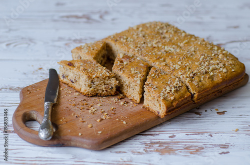 Homemade nuts and honey cake with knife lying near on wooden surface photo