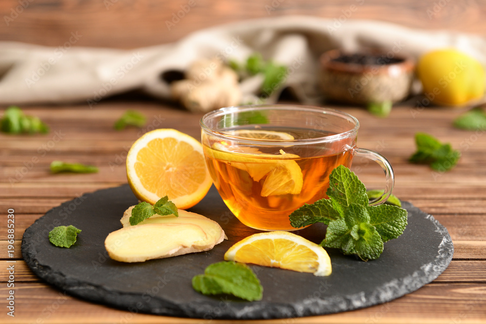 Glass cup of aromatic tea with lemon and ginger on slate plate Glass cup of aromatic tea with lemon and ginger on slate plate