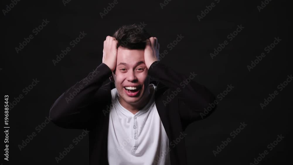An attractive young man showing big surprise against a black background. Medium Shot An attractive young man showing big surprise against a black background. Medium Shot