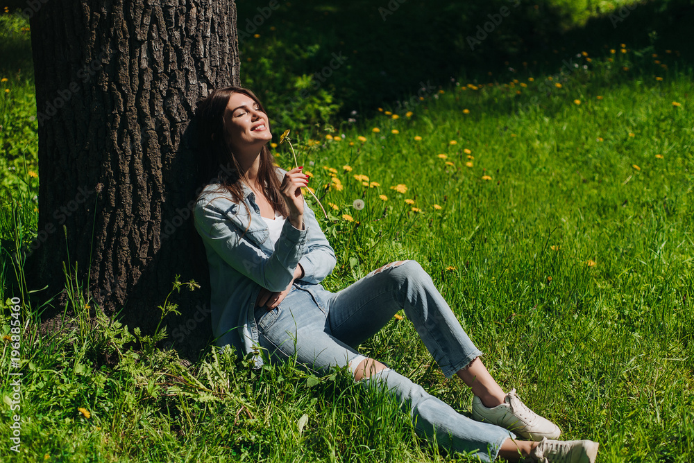 Woman smelling flower sitting on lawn Woman smelling flower sitting on lawn