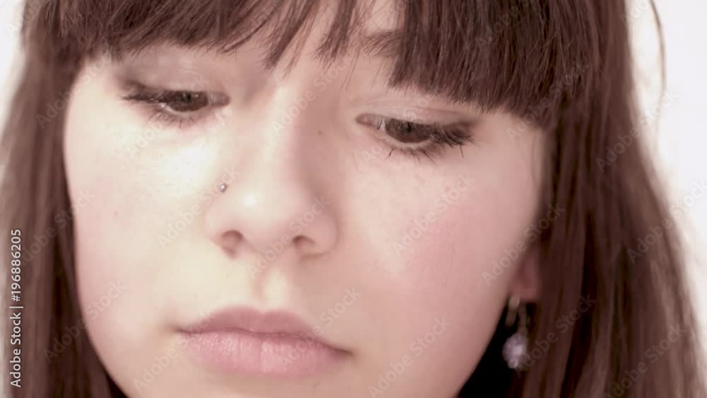 Serious young woman looking down lifts her head and looks at camera Serious young woman looking down lifts her head and looks at camera