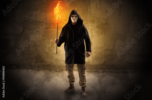 Wayfarer with burning torch in front of crumbly wall concept