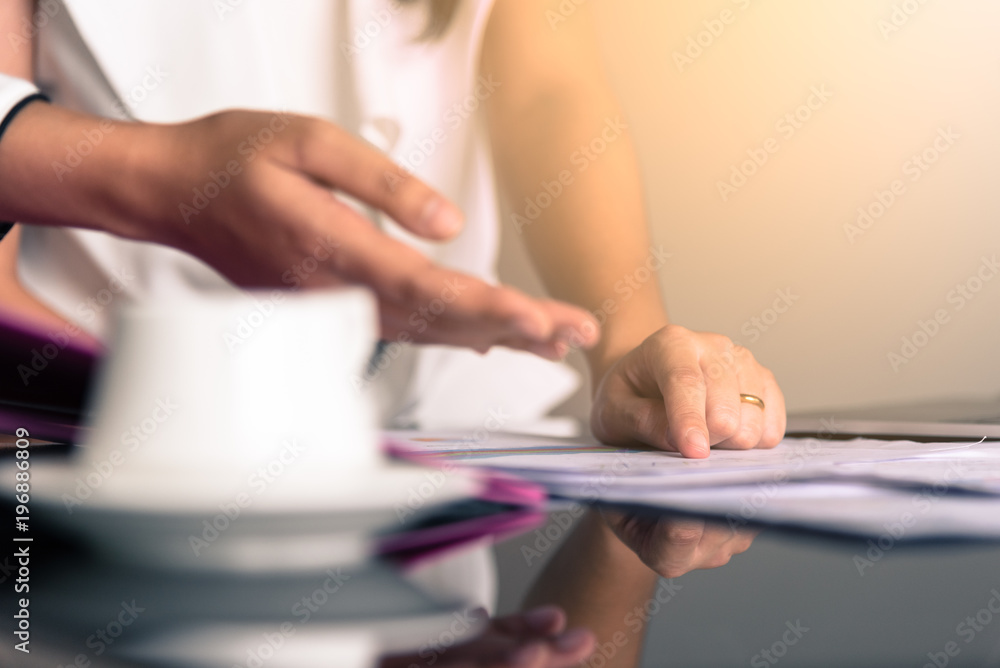 Hand of businesswoman writing on paper with pointing on documents in the office interrior