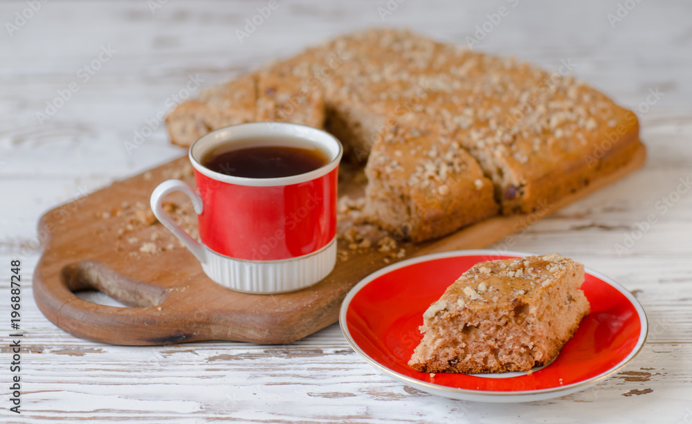 Cup of hot tea and piece of honey cake on red saucer. Rustic style. Cup of hot tea and piece of honey cake on red saucer. Rustic style.