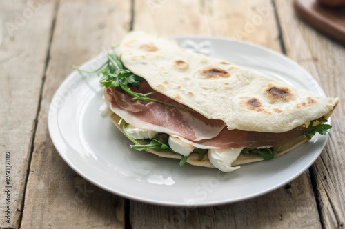 Homemade Italian flatbread called piadina with rocket salad, prosciutto and ricotta cheese.