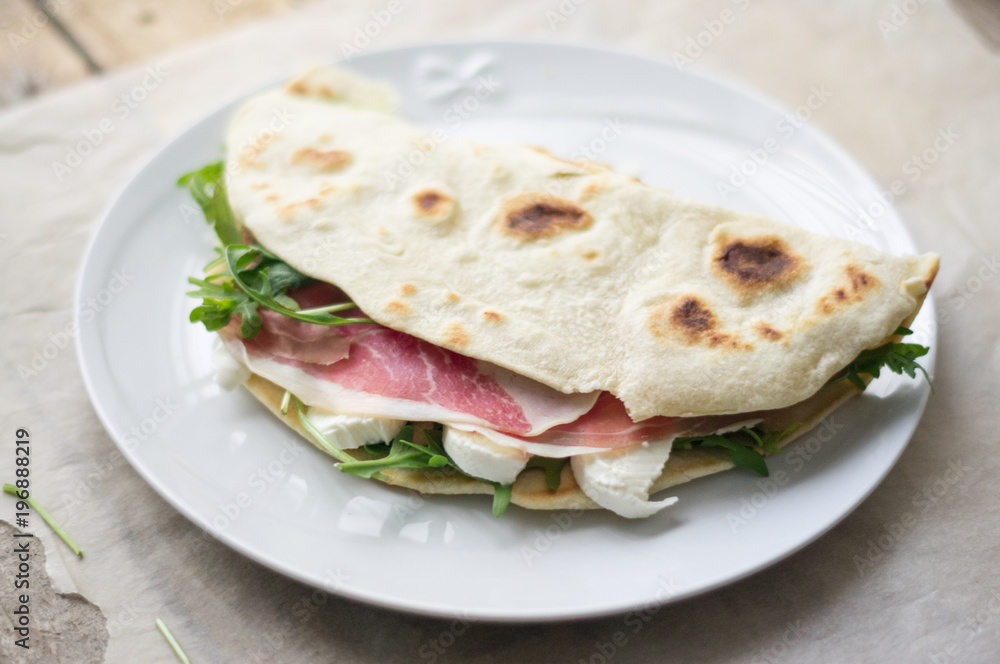 Homemade Italian flatbread called piadina with rocket salad, prosciutto and ricotta cheese. Homemade Italian flatbread called piadina with rocket salad, prosciutto and ricotta cheese.