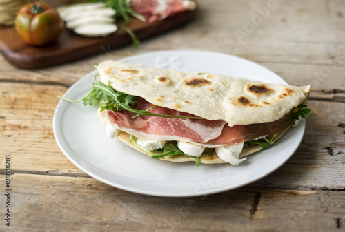 Homemade Italian flatbread called piadina with rocket salad, prosciutto and ricotta cheese.