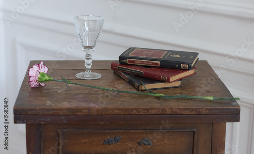 Una copa, una rosa y libros en la mesa
