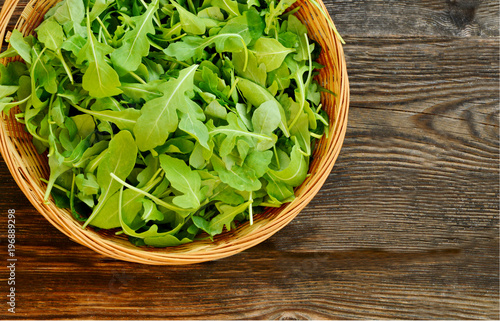 Arugula, rocket and rucola in the basket on wooden floor