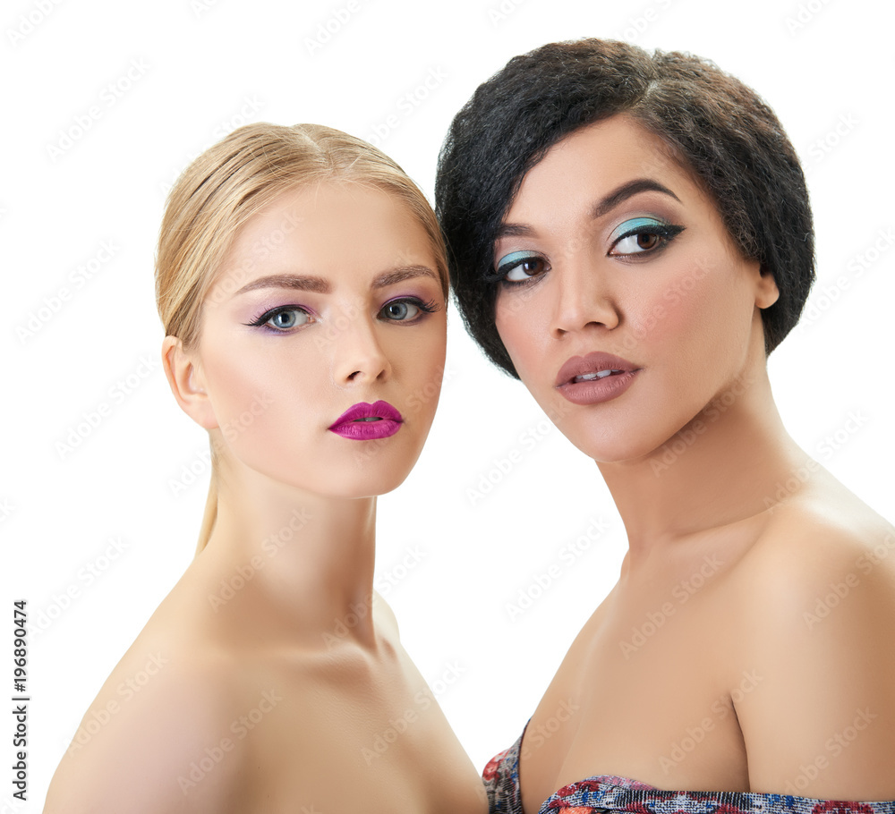 Makeup. Double female portrait. Caucasian blond girl and beautiful young woman posing in studio over white background. Fashion, beauty, glam, youth. Makeup. Double female portrait. Caucasian blond girl and beautiful young woman posing in studio over white background. Fashion, beauty, glam, youth.