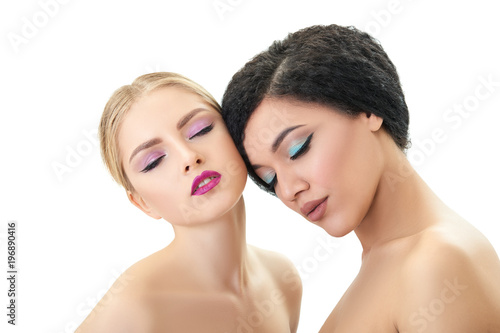 Makeup. Double female portrait. Caucasian blond girl and beautiful young woman posing in studio over white background. Fashion, beauty, glam, youth.
