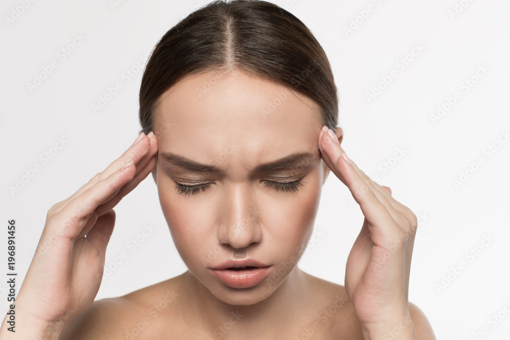 Terrible headache. Portrait of young woman is standing with closed eyes and touching her head while suffering from pain. Isolated background Terrible headache. Portrait of young woman is standing with closed eyes and touching her head while suffering from pain. Isolated background
