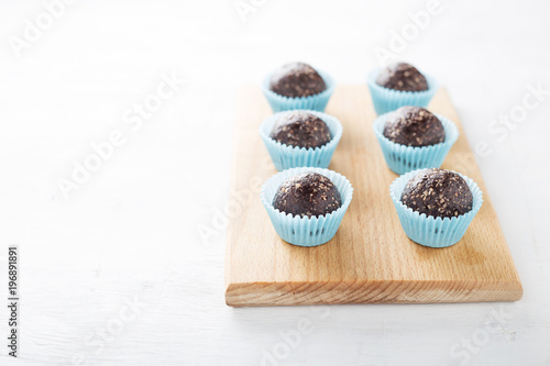Homemade healthy gluten-free no bake brownie energy bites on cutting board on the white table.