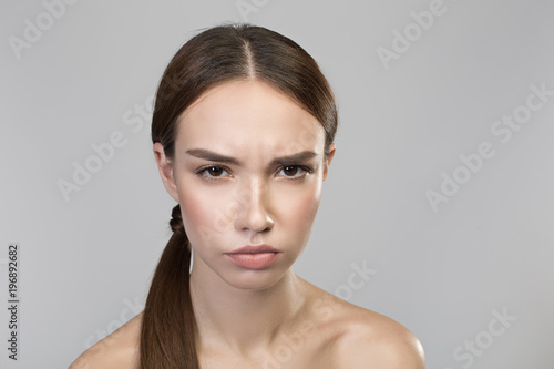 Feeling anger. Portrait of young disappointed naked woman is looking at camera with annoyance. Isolated background