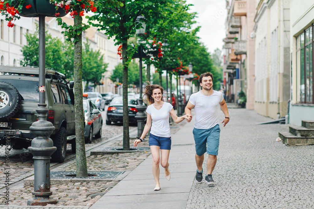 guy with a girl running on the sidewalk in the summer