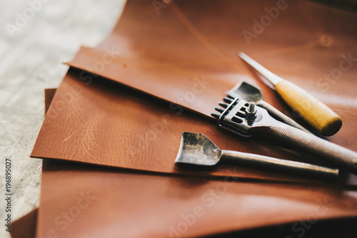 Crafting tools on natural cow leather in the tailoring workshop. Top view.