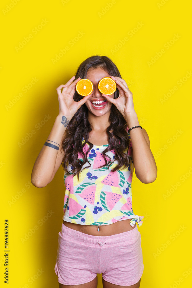 Fashion summer portrait funny indian girl with oranges over yellow background. Diet cincept Fashion summer portrait funny indian girl with oranges over yellow background. Diet cincept
