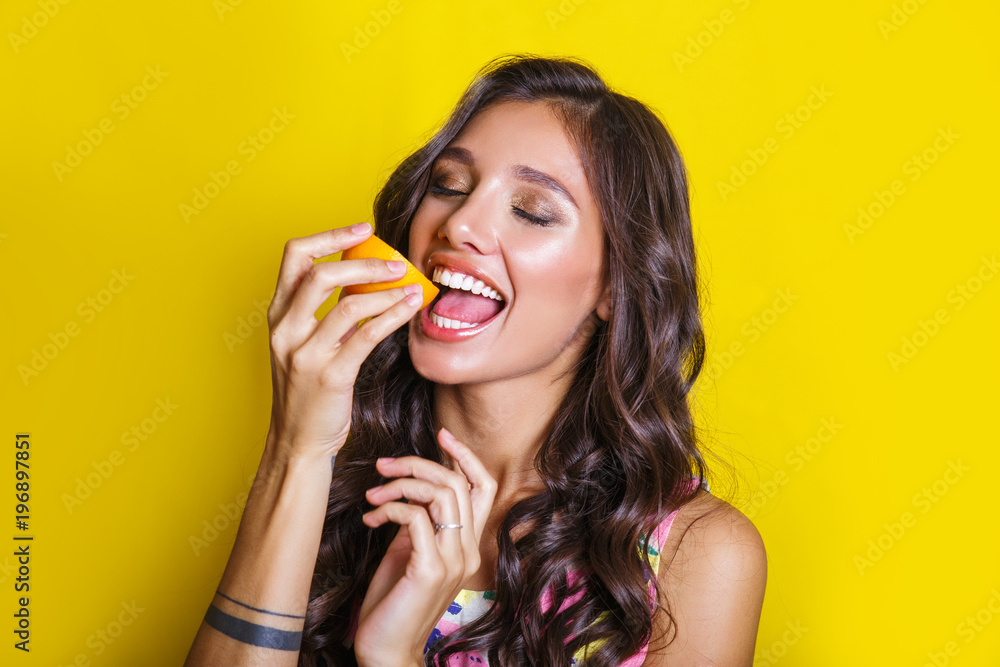 Fashion summer portrait funny indian girl with oranges over yellow background. Diet cincept Fashion summer portrait funny indian girl with oranges over yellow background. Diet cincept