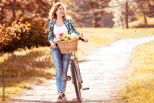 Beautiful girl and bicycle with flowers in basket at park