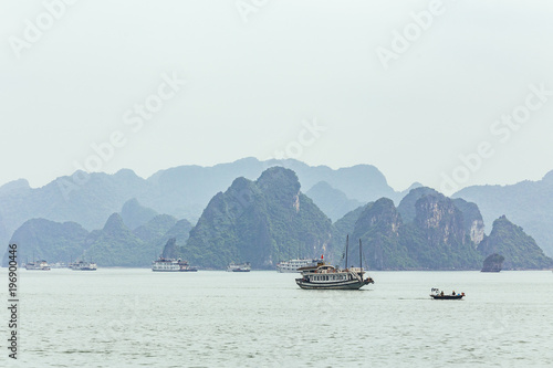 Seascape with towering limestone islands over emerald water with growing trees on it that view from cruising tourist boat in summer at Quang Ninh, Vietnam.