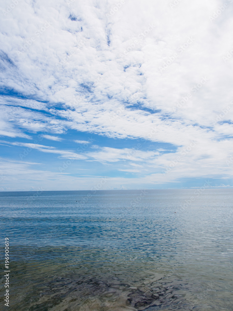 Fototapeta premium Wide angle view of calm ocean waters with a beautiful stratocumulus cloud formation on a sunny day. Hua Hin, Thailand. Travel and nature concept.
