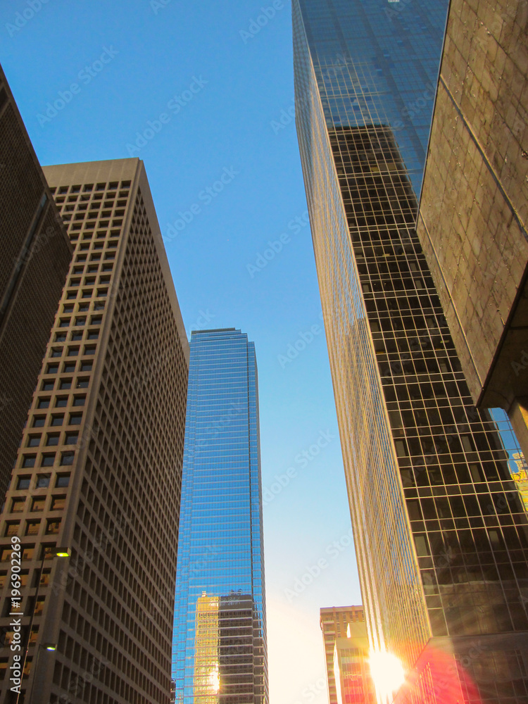 Fototapeta premium Street skyline of modern buildings against a blue sky in downtown of Dallas, Texas, USA. Open free scenic view of American skyscrapers and architecture of city center district.