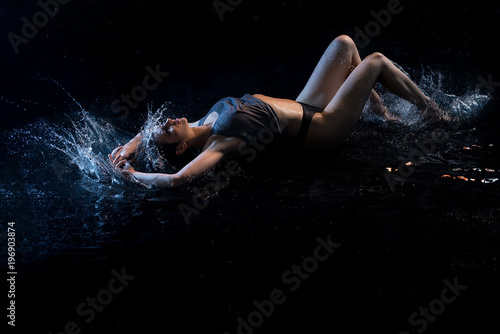 Sexy girl lying in water in the dark
