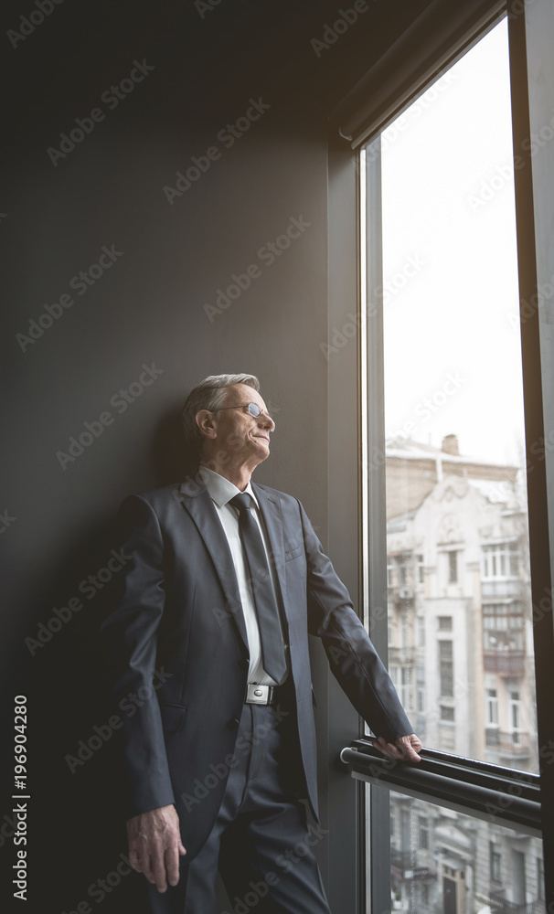 Fototapeta premium Side view pleased retire male watching at street during break at work. Relax at labor concept