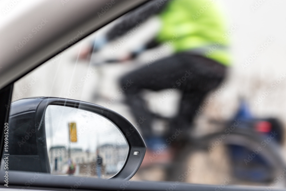 Part inside view of a car, a car mirror and a partial view of a cyclist Part inside view of a car, a car mirror and a partial view of a cyclist