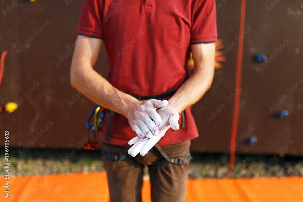 Close up of climber man coating hands in powder chalk magnesium and preparing to climb workout outdoor training rock wall. Close up of climber man coating hands in powder chalk magnesium and preparing to climb workout outdoor training rock wall.