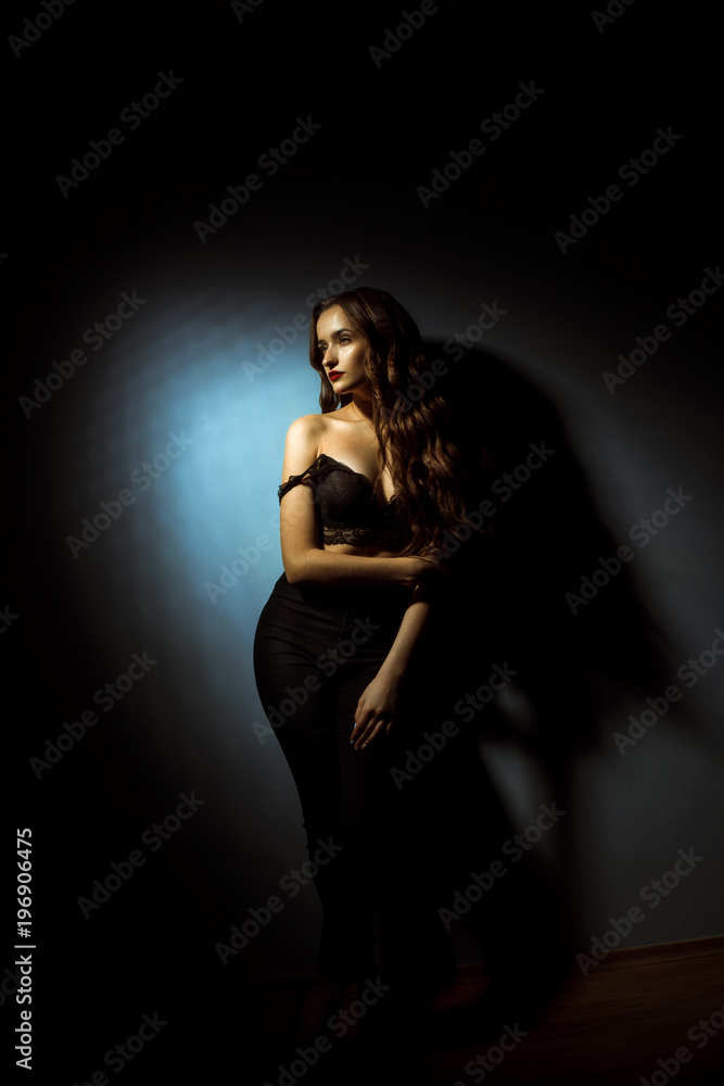 Gorgeous lady with curly hairstyle in dark studio