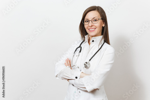 Smiling confident beautiful young doctor woman with stethoscope, glasses isolated on white background. Female doctor in medical gown holds hands folded. Healthcare personnel, health, medicine concept.