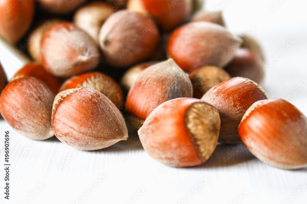 Walnut hazelnuts scattered on a white wooden table. Walnut hazelnuts scattered on a white wooden table.
