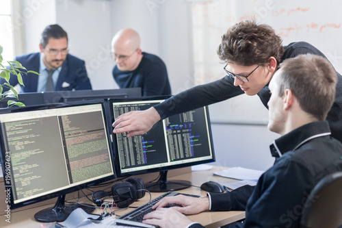 Obraz w ramie Startup business and entrepreneurship problem solving. Young AI programmers and IT software developers team brainstorming and programming on desktop computer in startup company share office space.