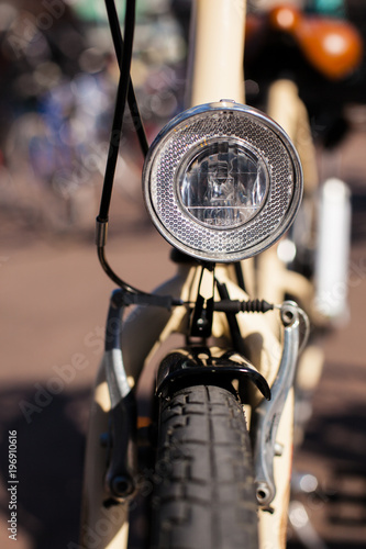 Close-up of the Headlight of a white Bicycle with brown Saddle