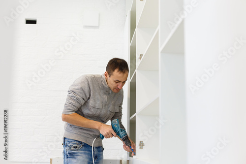Carpenter screwing solid maple cabinets into the wall white spot in drill