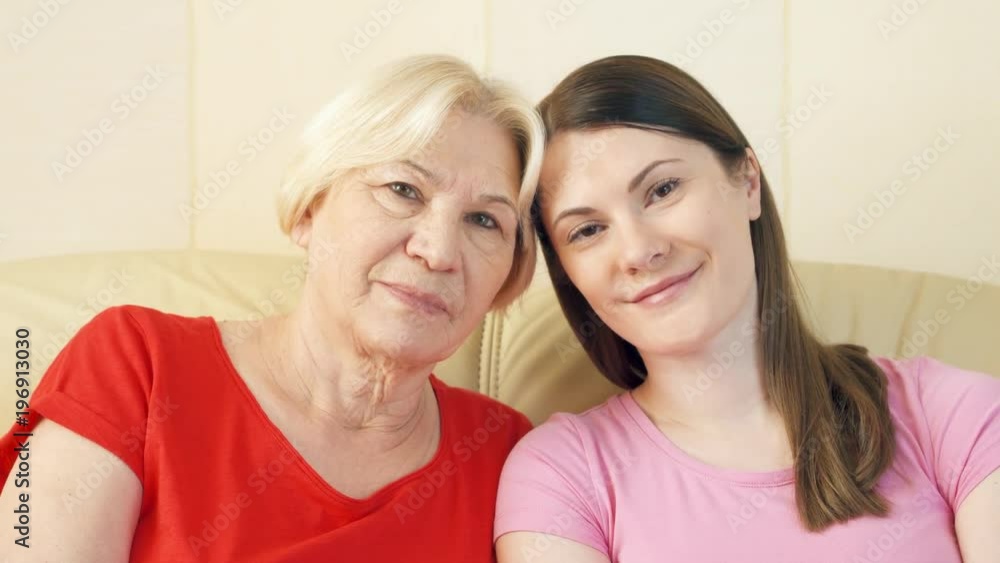 Portrait of senior mother and her young teen daughter relaxing on sofa at home. Happy family enjoying time together. Portrait of senior mother and her young teen daughter relaxing on sofa at home. Happy family enjoying time together.