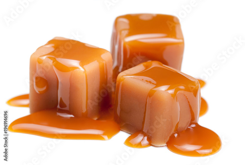 Caramel candies with caramel sauce isolated on a white background close up. 