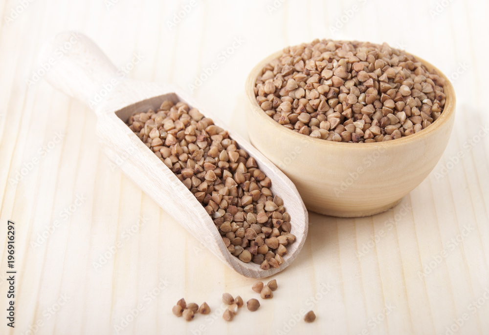 Buckwheat groats in a wooden bowl and in a wooden spoon Buckwheat groats in a wooden bowl and in a wooden spoon