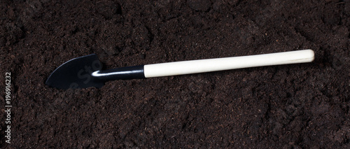 Black iron shovel on the peatmoss soil. Close-up of the organic ground, and spade photo