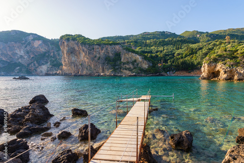 Wooden pier in Paleokastritsa bay with sand and crystal sea water. Corfu island  Greece.