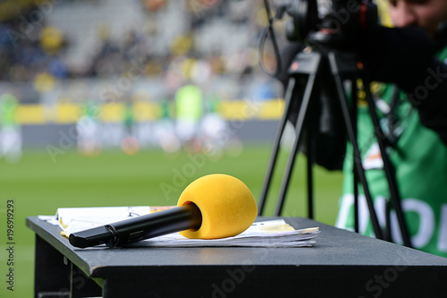 Gelbes Mikrofon auf TV Moderationspult im Stadion
