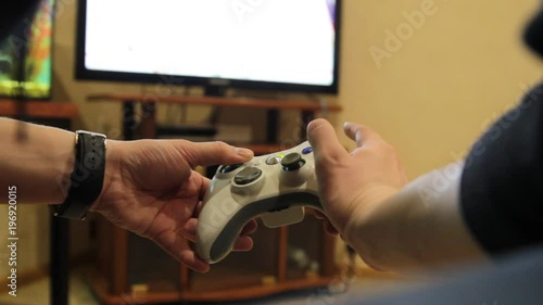 Closeup of young man hands playing video games on gaming console in front of TV widescreen