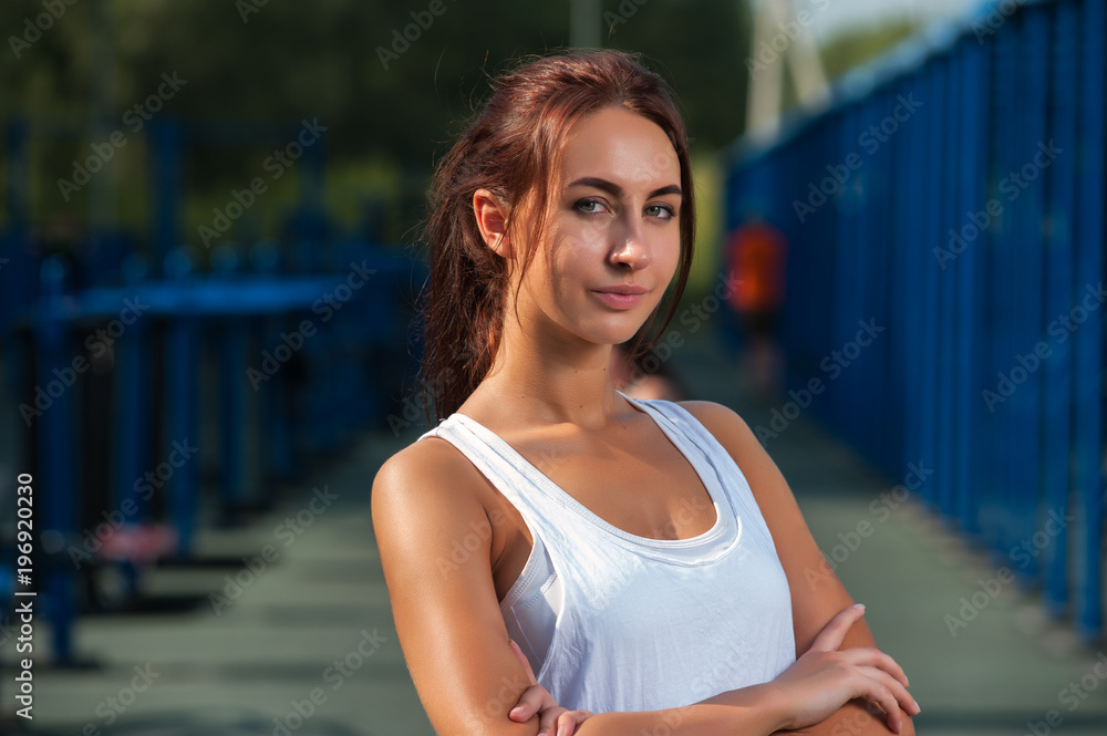Portrait of young sporty woman exercising in outdoors gym at summer sunny day
