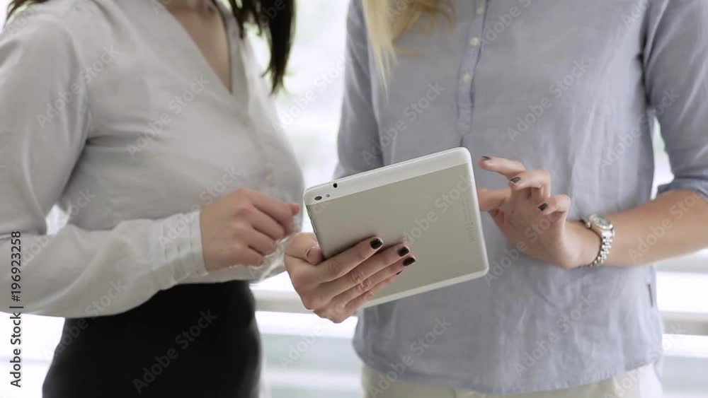 Young Beautiful Businesswomen Standing And Using Tablet Young Beautiful Businesswomen Standing And Using Tablet
