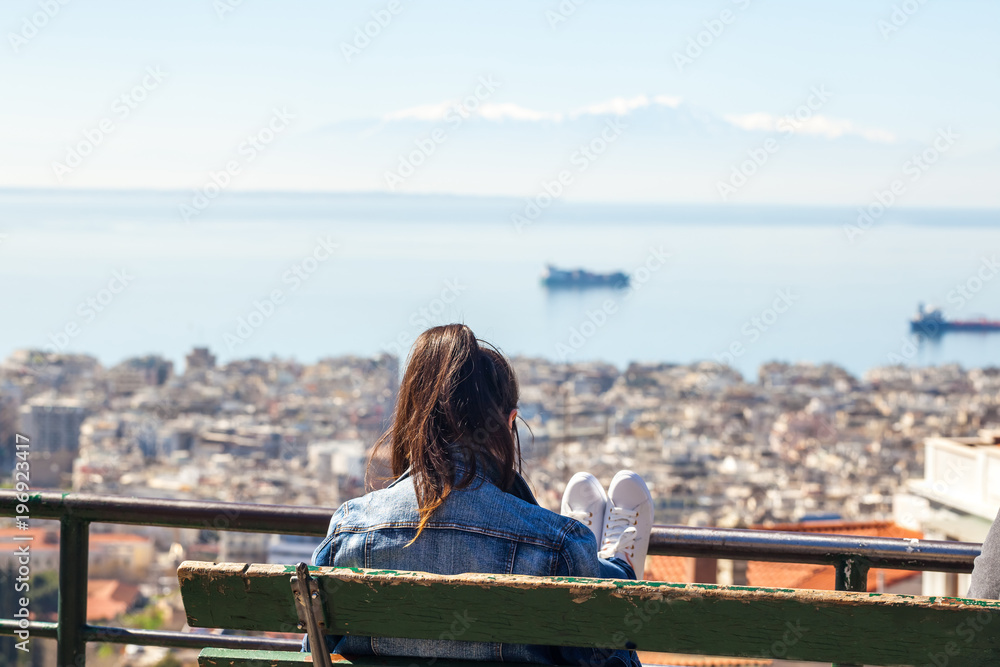 Girl sitting on a bench looking at the gulf in Thessaloniki, Greece